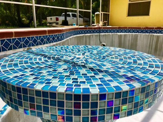 Glass tiled table top for a conversation pit in a pool