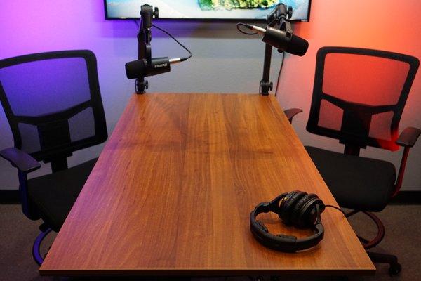 Podcast room set up for an interview with table-mounted microphone arms.