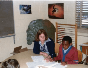 Dr. Stone with a child completing his work in class.