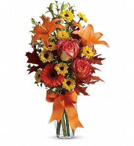 A burst of beauteous blooms in autumn shades of orange and yellow is mixed with a handful of oak leaves.