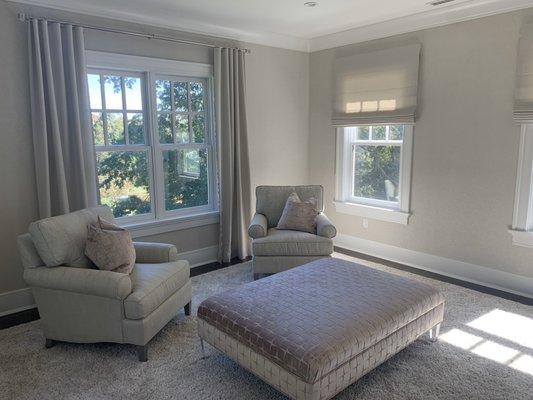 Drapery on a Modern track,Roman shades and a Ottoman on lucite legs.