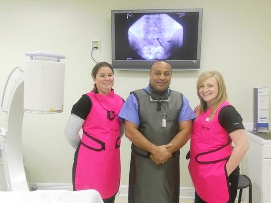 Dr. Hamed (middle) examining the results of a patient's spine x-ray with two staff members.