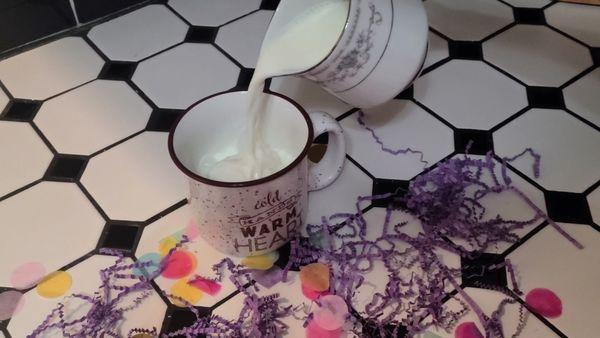 Pouring the warm milk over the cocoa bomb