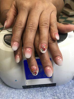 Fake nails with powdered ombré with a butterfly and a flower on top.