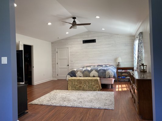 Ship lap accent wall in master bedroom with laminate flooring, light fixtures and fan. New windows installed all the way around.