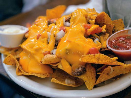 Nachos $7.99 Tortilla chips topped with melted cheese, tomato, onion and  beef.