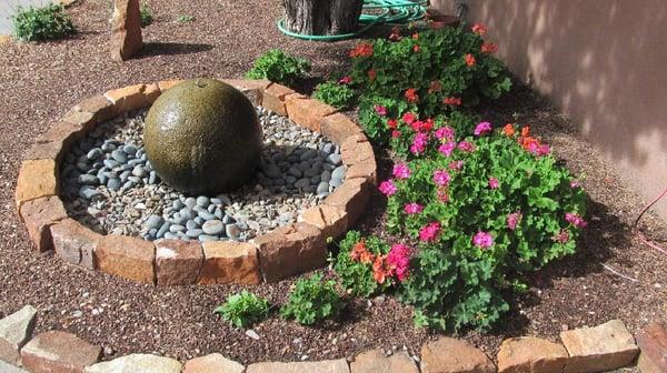 Hand-chiseled rock border, fountain, and simple, colorful landscaping