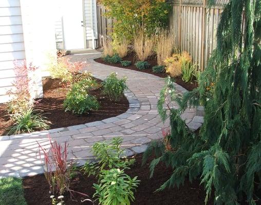 Paver path, barkdust, and shrubs.