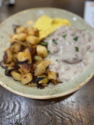 Turkey sausage with gravy on top of it biscuit with home fries  and scrambled eggs