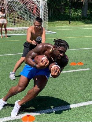 Pictured: Tyler Goodson (former Iowa Football running back) practicing an agility drill while Jonathan (videographer) records it.