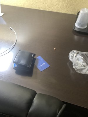 In my hotel room on the desk at the Clarion Inn, there is a cockroach next to my hotel room key (Clarion Inn) and my wallet.