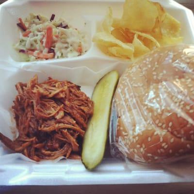 Pulled pork sandwich with coleslaw and kettle chips and a pickle