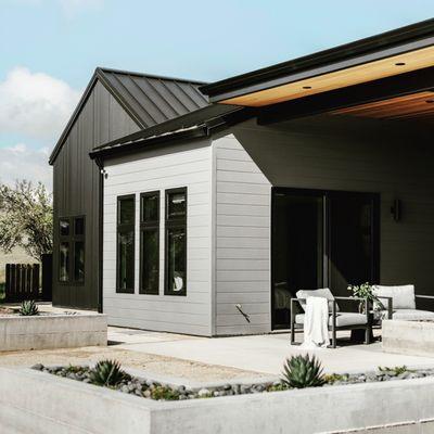 Exterior of a modern farmhouse, cladded with black metal siding and windows.