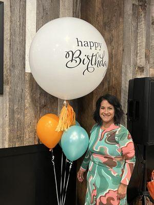 This is the birthday girl with one of many balloon bouquets that were around the room.