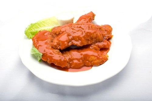 Delicious buffalo tenders on a plate, drizzled with sauce and topped with fresh lettuce from Genova's To Go.