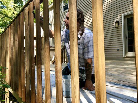 Adam carefully applies some stain to this porch railing.