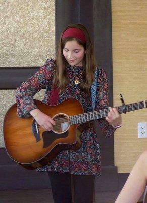 Student playing guitar during recital