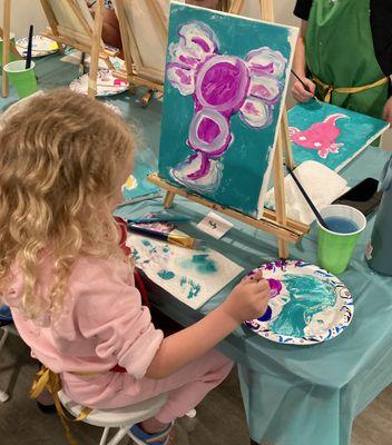 Little artist at work painting her purple Axolotl during a public event