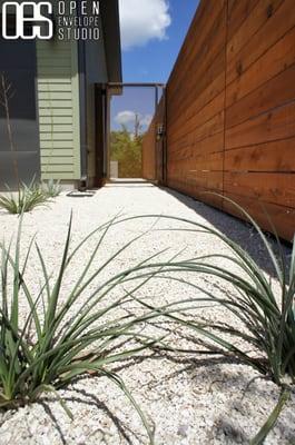 Wilson Residence: Native plants with crushed limestone, horizontal fence, and custom steel entry gate.