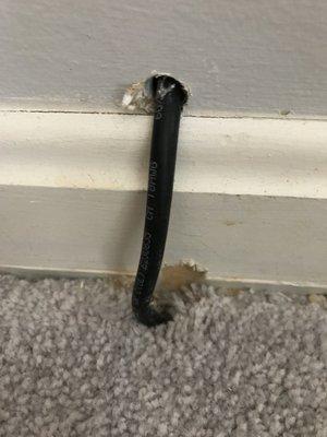 Exposed wire and ruined baseboard. Is this even to code?