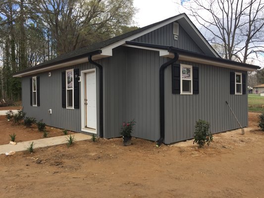 Old house with new vinyl board and batten siding with new black gutters