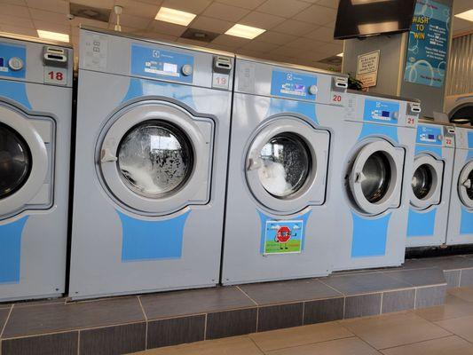 Large capacity washers in action. To the left are medium, then small washing machines.