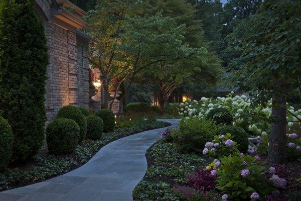 Transforming walkways with vibrant flowers, shrubs, trees, and ground cover plants complemented by mulch for a picturesque landscape stroll