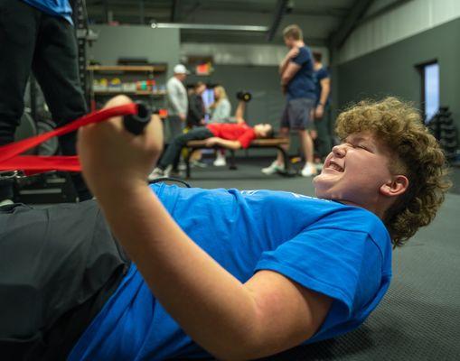 Middle school football athlete using our Keiser functional trainer.