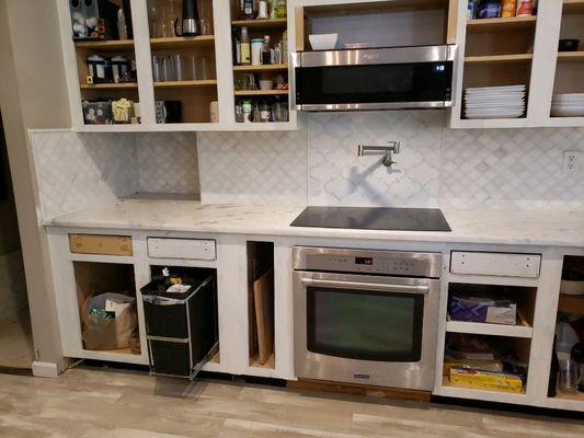 A kitchen  remodeling  job in full progress.. showing  this custom built backsplach and white granite countertops.