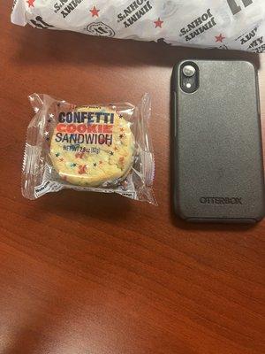 Tiny cookie next to iPhone.