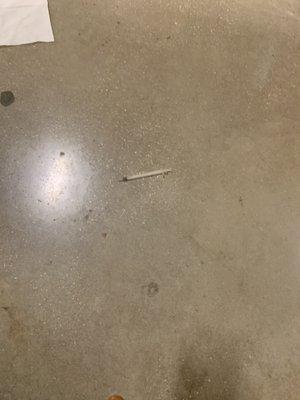 Dirty needle on floor of restroom.