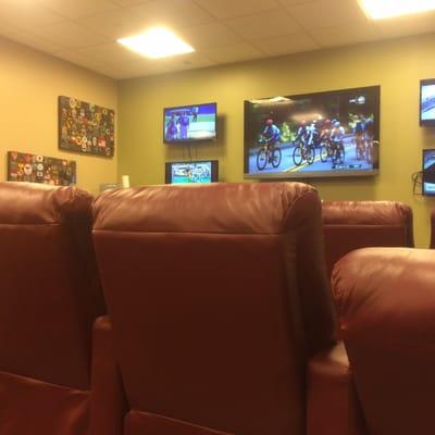 Big comfy leather chairs w 5 TVs on wall