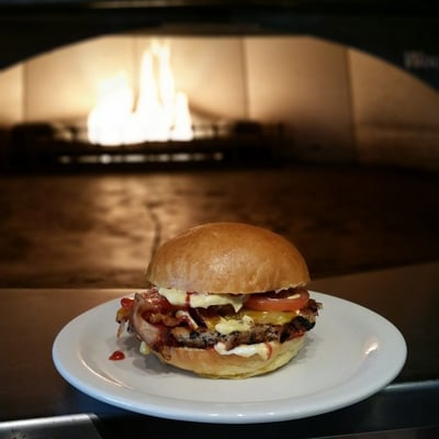 Beautiful shot of the Three grain veggie burger made custom, in front of the brick oven where bread and pizza is made fresh!