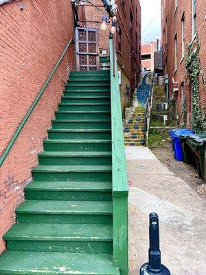 stairway to pub on second level and 2'd stairway from street level with a peacock mural