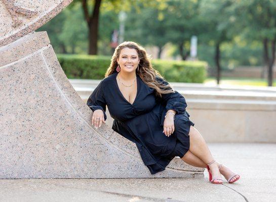 College of Education senior woman wearing a black dress during a senior session and is posed at the Seal on TTU Campus.