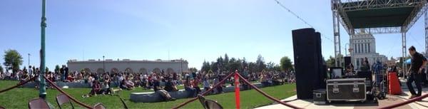 People sat on grass or steps. Dancing in front of stage.