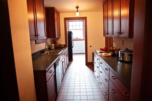 Galley kitchen, including plenty of counter space, large residential size fridge, double sink, and dishwasher.