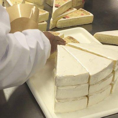 Custom cut and handwrapped Brie being labeled.