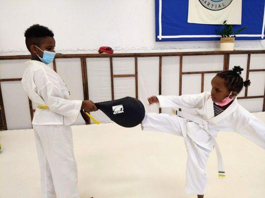 Siblings practicing their round kicks after class