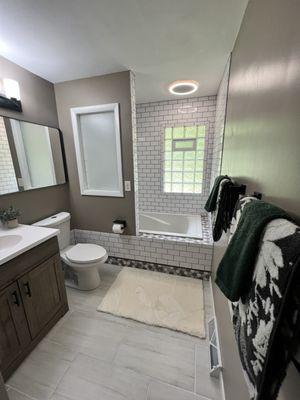 Total bathroom remodel. Design by Maeko. Paint, tile install, vanity, toilet, mirror, light fixtures, towel rack, window, flooring by Maeko.