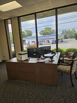 The open space desk next to the large window.