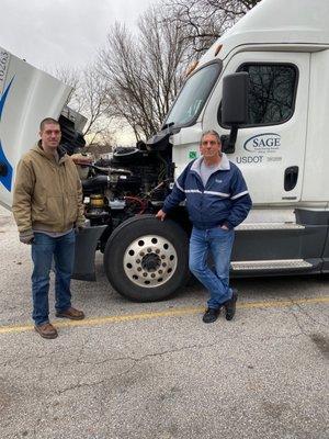 Student and instructor from Sage posing after inspecting front end of training vehicle.