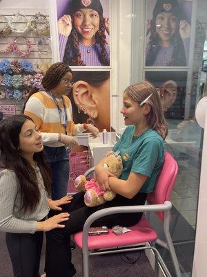 Piercing station. My daughter, her bestie, and our hero of the day.