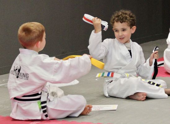 Happy kids at Kickboxing Plus Martial Arts Academy celebrating their new belts, showcasing their progress and achievements.