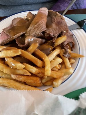 Hot Roastbeef with French fries topped with brown gravy.