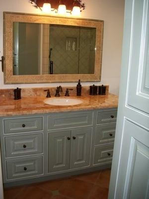 Onyx counter top with a custom tiled shower shown in the mirror.