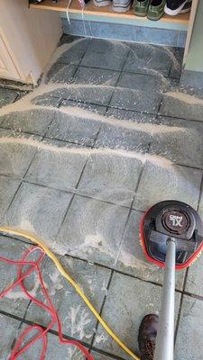 Scrubbing the dirty tile and grout before the steam cleaning.