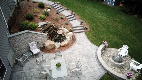 Patio, steps, sitting wall, fire pit, veneered wall, waterfall and pond, new plantings for a customer in Tolland.