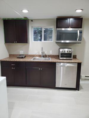 Kitchen installation in an unfinished basement to include ceiling, walls, and floor.