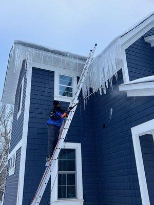 Removing an ice dam from a ladder in Minneapolis in January 2023.